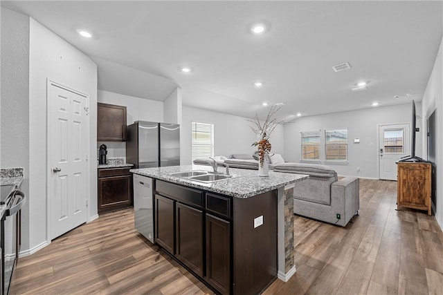 kitchen featuring hardwood / wood-style floors, sink, an island with sink, dark brown cabinetry, and stainless steel appliances