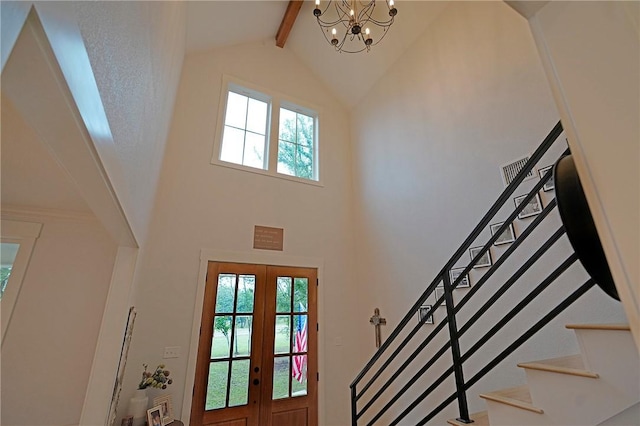 foyer entrance featuring a chandelier, beam ceiling, high vaulted ceiling, and french doors