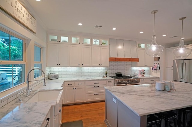 kitchen with pendant lighting, premium appliances, white cabinets, a center island, and custom exhaust hood