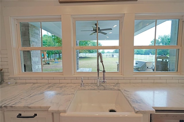 details with light stone countertops, white cabinets, decorative backsplash, sink, and ceiling fan