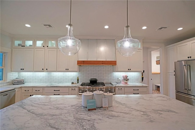 kitchen featuring light stone countertops, white cabinets, stainless steel appliances, decorative backsplash, and hanging light fixtures