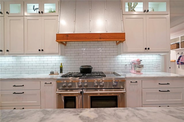 kitchen featuring white cabinets, double oven range, light stone countertops, and tasteful backsplash