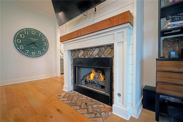 interior details with ornamental molding, hardwood / wood-style floors, and a tiled fireplace