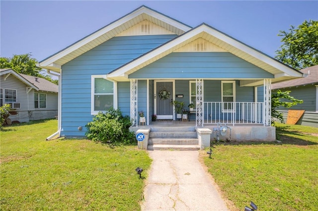 bungalow with a porch, a front lawn, and cooling unit