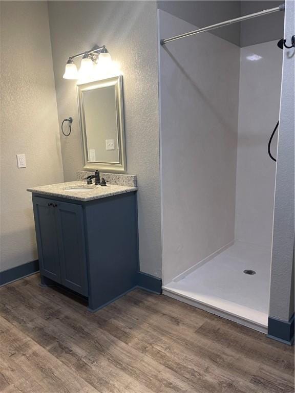 bathroom featuring hardwood / wood-style floors, vanity, and walk in shower