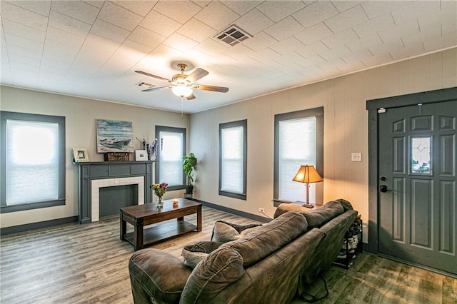 living room with a tile fireplace, wood-type flooring, and ceiling fan