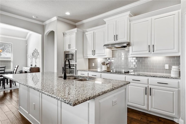 kitchen featuring dark wood finished floors, a sink, under cabinet range hood, white cabinetry, and stainless steel microwave