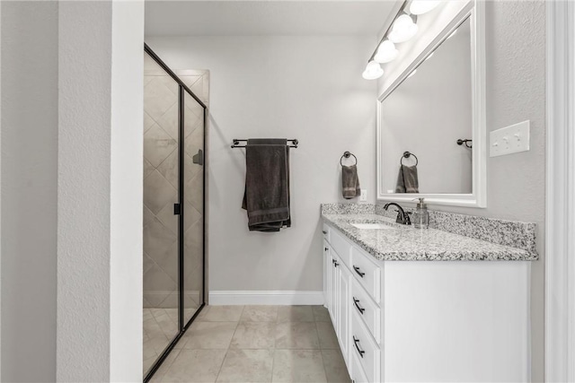 full bathroom with vanity, a shower stall, baseboards, and tile patterned floors