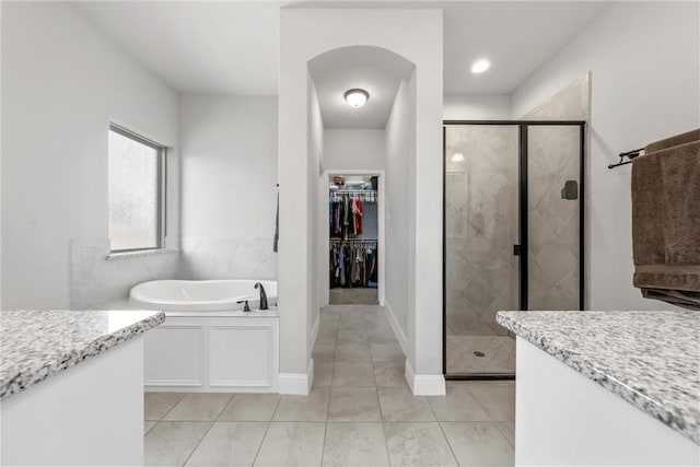 bathroom with a garden tub, a stall shower, tile patterned flooring, baseboards, and a spacious closet