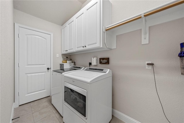 laundry room featuring cabinet space, light tile patterned floors, and washing machine and dryer