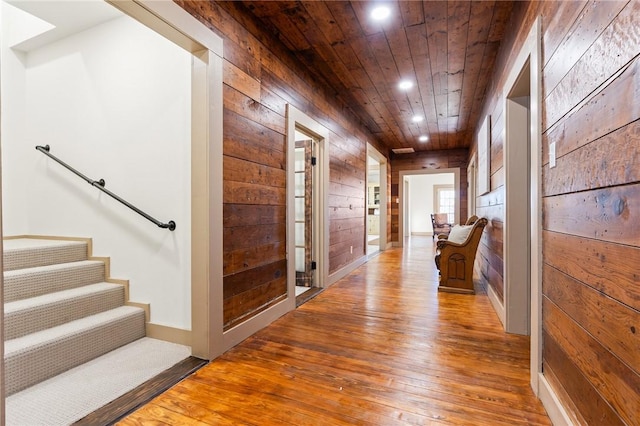 hallway featuring hardwood / wood-style floors, wood ceiling, and wood walls