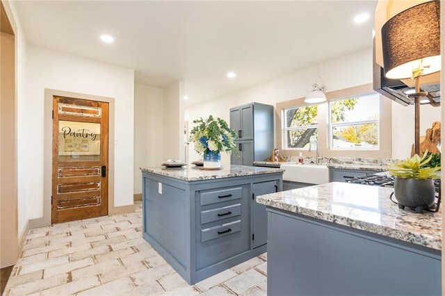 kitchen featuring sink, a center island, and light stone counters