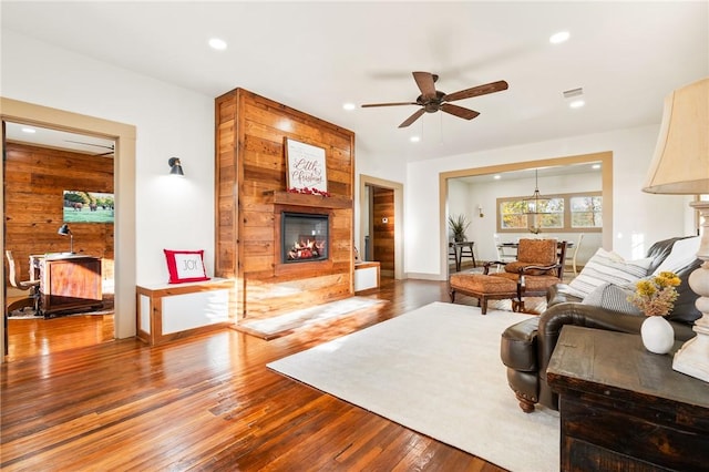 living room with wood walls, ceiling fan, and wood-type flooring