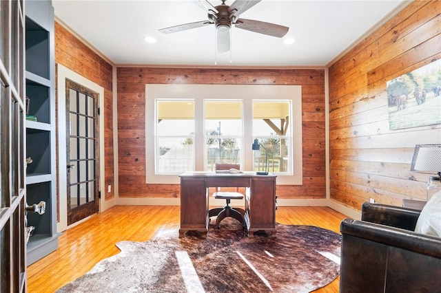 office space with ceiling fan, light wood-type flooring, and wooden walls