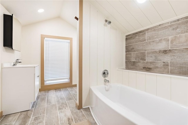 bathroom with bathing tub / shower combination, vaulted ceiling, wood walls, and vanity