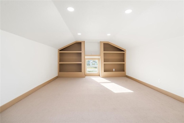 additional living space with light carpet, built in shelves, and lofted ceiling