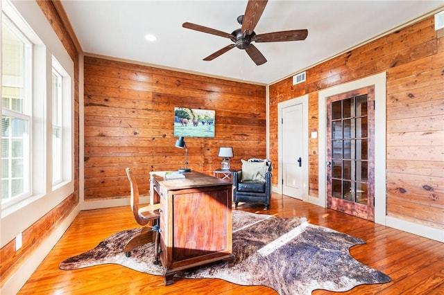 home office featuring wood walls, plenty of natural light, and wood-type flooring