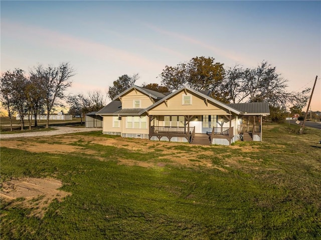 back house at dusk with a yard and a porch