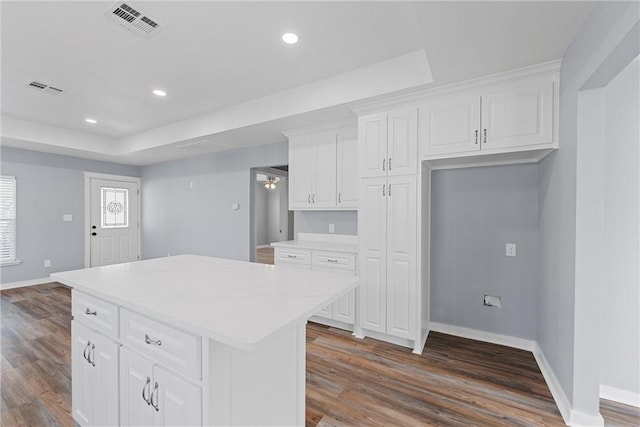 kitchen with white cabinets, ceiling fan, a kitchen island, and dark hardwood / wood-style flooring