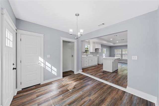 interior space featuring pendant lighting, an inviting chandelier, white cabinets, sink, and dark hardwood / wood-style flooring