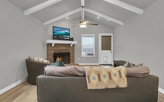 living room featuring vaulted ceiling with beams, light wood-type flooring, a fireplace, and baseboards