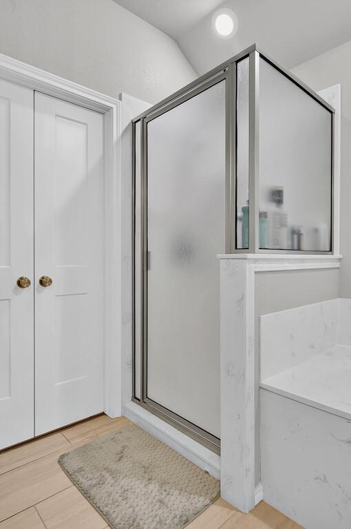 full bathroom featuring a stall shower and wood finished floors