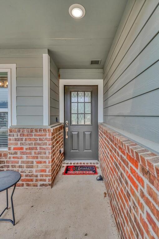 entrance to property with visible vents and brick siding