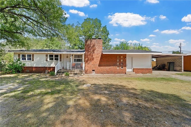 back of property with a yard, covered porch, and a carport