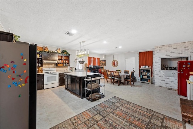 kitchen featuring a breakfast bar, electric range, a textured ceiling, decorative light fixtures, and a kitchen island