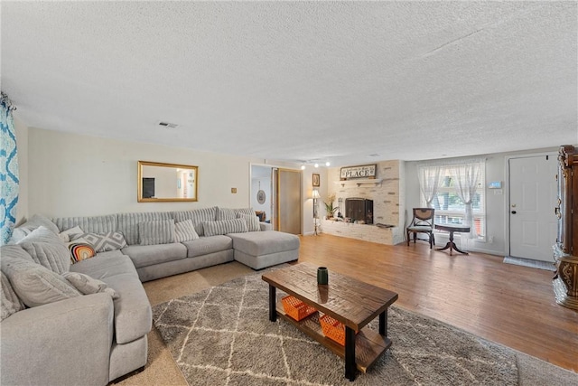 living room featuring hardwood / wood-style floors, a textured ceiling, and a brick fireplace