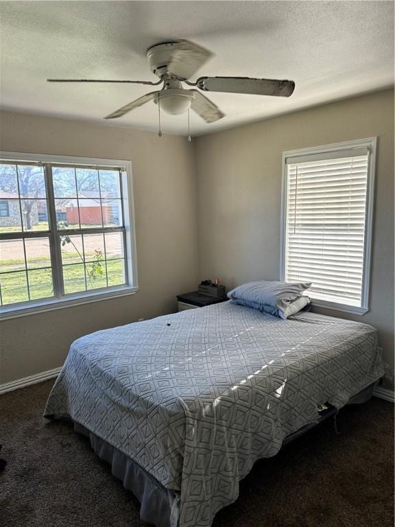 bedroom featuring multiple windows, ceiling fan, and dark colored carpet