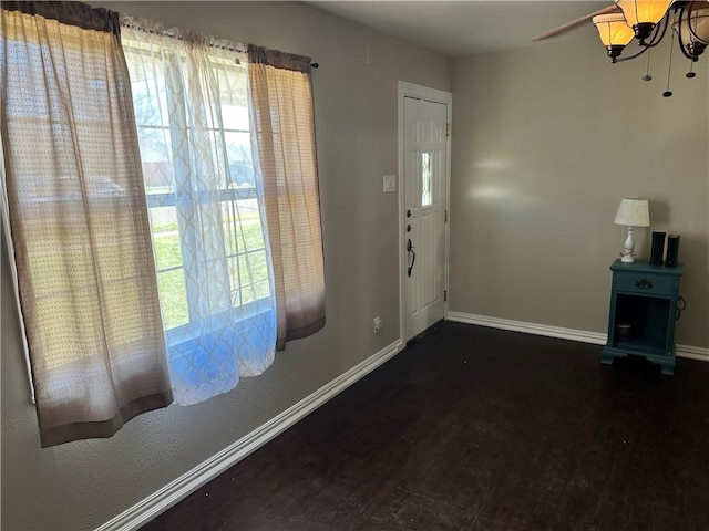 entrance foyer with ceiling fan with notable chandelier and dark hardwood / wood-style floors