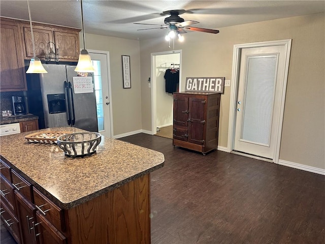 kitchen featuring ceiling fan, pendant lighting, stainless steel fridge with ice dispenser, dark hardwood / wood-style floors, and a kitchen island