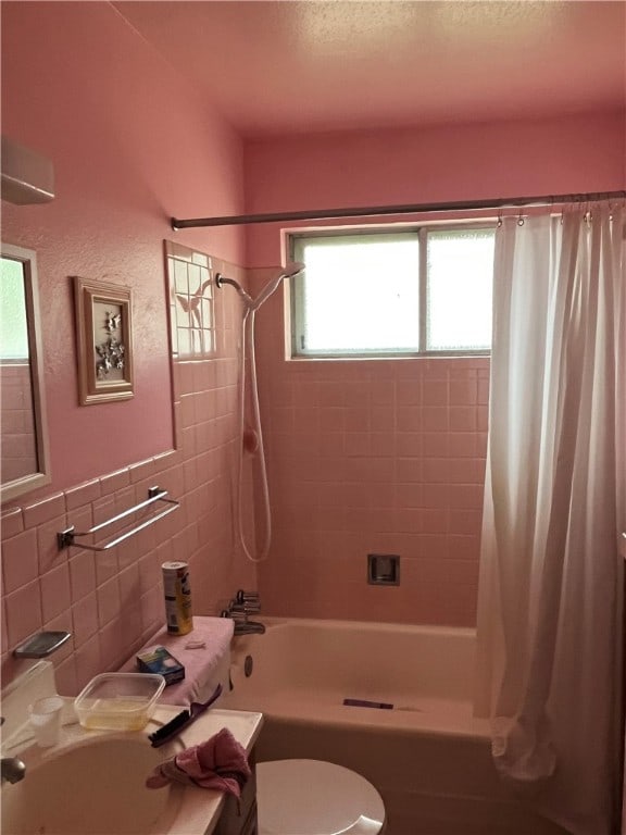 bathroom with tile walls, toilet, a wealth of natural light, and shower / bath combination with curtain