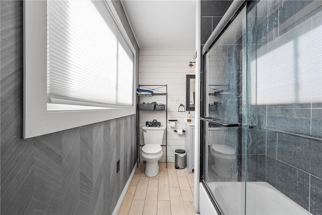 bathroom featuring bath / shower combo with glass door and toilet