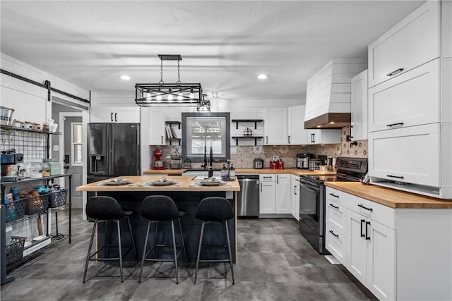 kitchen featuring a kitchen island, appliances with stainless steel finishes, a breakfast bar, butcher block countertops, and white cabinetry