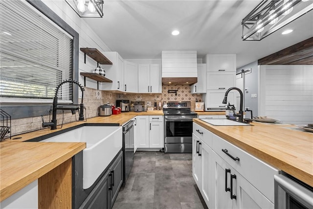 kitchen featuring sink, butcher block countertops, dishwasher, stainless steel range with electric stovetop, and white cabinets