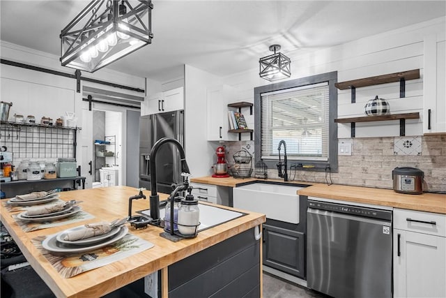 kitchen featuring stainless steel appliances, sink, pendant lighting, and butcher block countertops