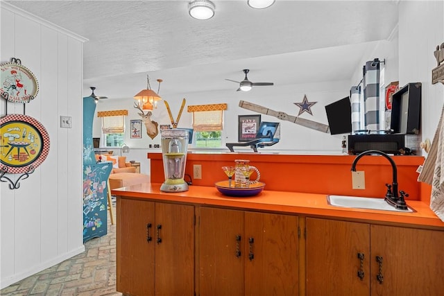 kitchen with a textured ceiling, ceiling fan, sink, and hanging light fixtures