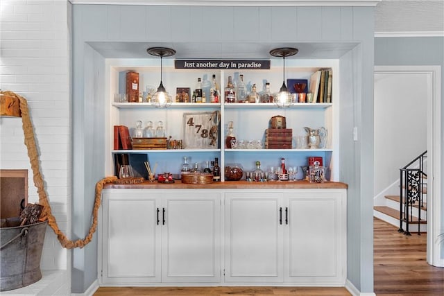 bar featuring ornamental molding, pendant lighting, and wood-type flooring