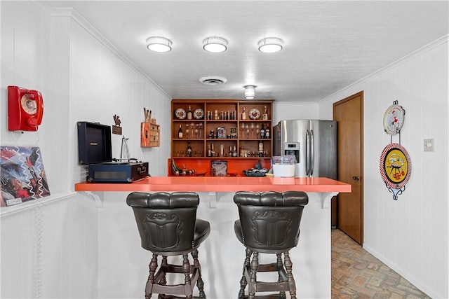 kitchen featuring a kitchen breakfast bar, crown molding, stainless steel fridge with ice dispenser, and kitchen peninsula