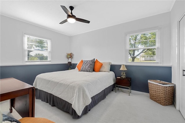 bedroom with light colored carpet, multiple windows, and ceiling fan