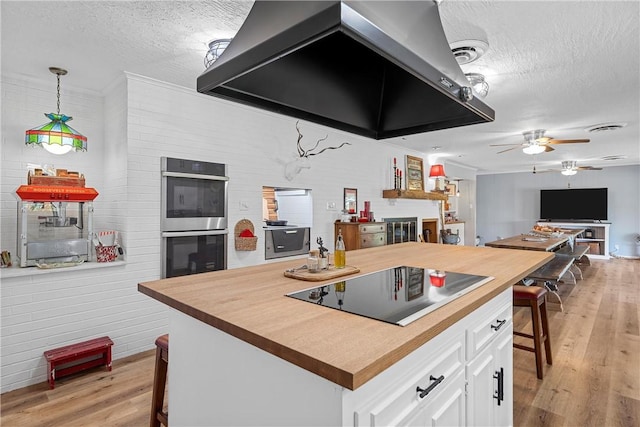 kitchen with black electric stovetop, extractor fan, double oven, white cabinetry, and a breakfast bar area