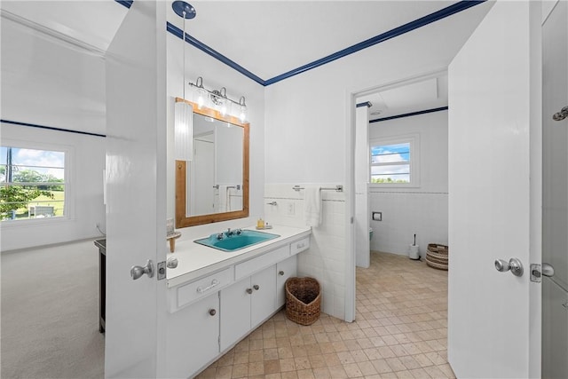 bathroom with vanity, a wealth of natural light, and tile walls