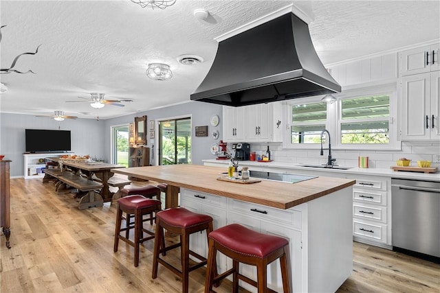 kitchen featuring wood counters, dishwasher, white cabinets, a kitchen breakfast bar, and island exhaust hood