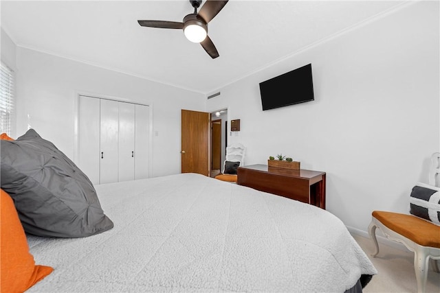 carpeted bedroom with ceiling fan, ornamental molding, and a closet