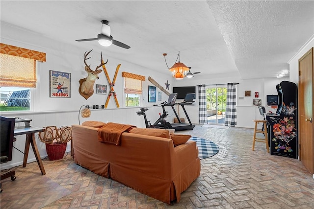 living room featuring ceiling fan with notable chandelier and a textured ceiling