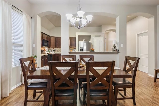 dining area with light wood-type flooring and an inviting chandelier