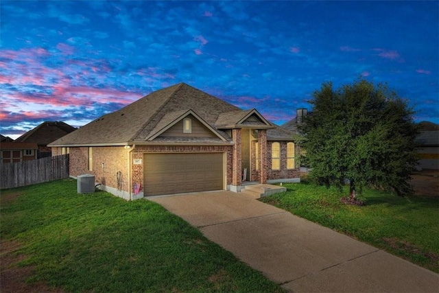 view of front of home with cooling unit, a garage, and a yard