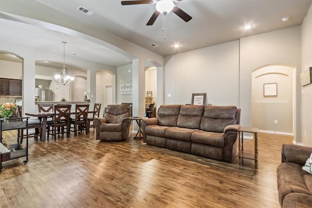 living room with ceiling fan with notable chandelier and hardwood / wood-style flooring